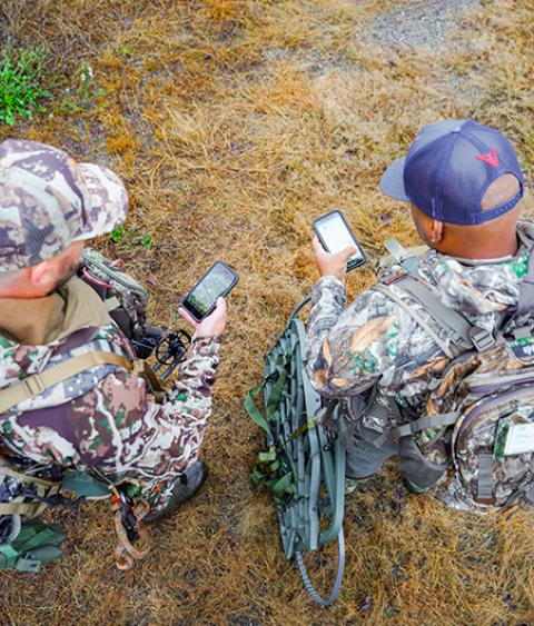 Two archery hunters looking at mobile devices