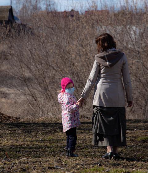 Mother and daughter outdoors wearing protective masks