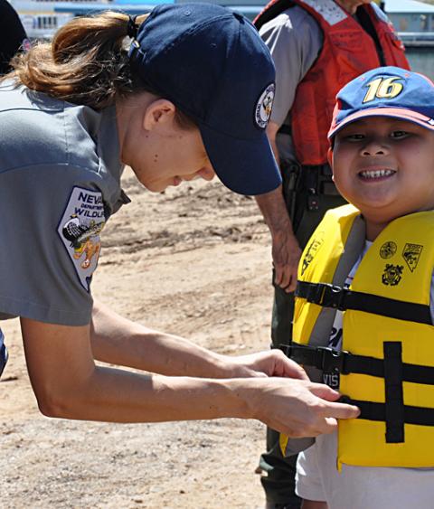 State agency staff helps with a lifejacket