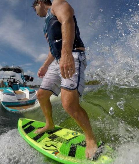 Wakeboarder riding a wake from a wakeboat