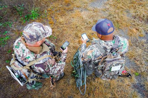 Two archery hunters looking at mobile devices