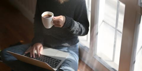 Woman viewing laptop drinking coffee
