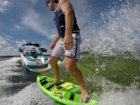 Wakeboarder riding a wake behind a wakeboat